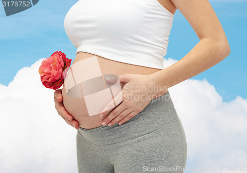 Image of close up of pregnant woman touching her bare tummy