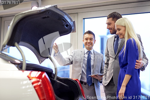 Image of happy couple with car dealer in auto show or salon