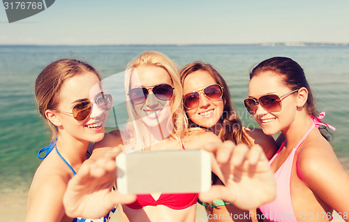 Image of group of smiling women making selfie on beach