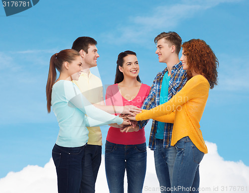 Image of smiling teenagers with hands on top of each other