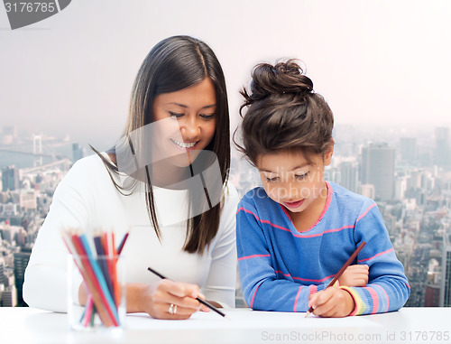 Image of happy mother and daughter drawing with pencils