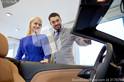 Image of happy couple buying car in auto show or salon