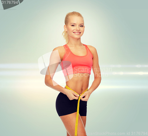 Image of smiling sporty woman with measuring tape