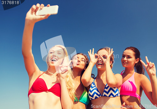Image of group of smiling women making selfie on beach