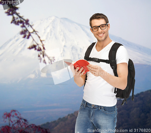 Image of happy young man with backpack and book travelling