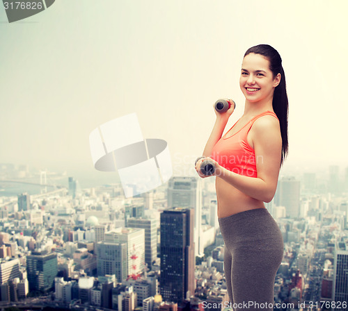 Image of young sporty woman with light dumbbells