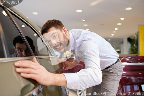 Image of happy man touching car in auto show or salon