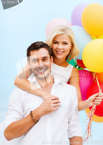 Image of couple with colorful balloons at seaside