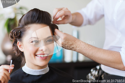 Image of happy woman with stylist making hairdo at salon