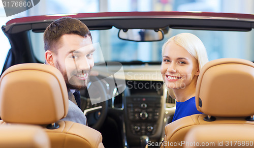 Image of happy couple sitting in car at auto show or salon