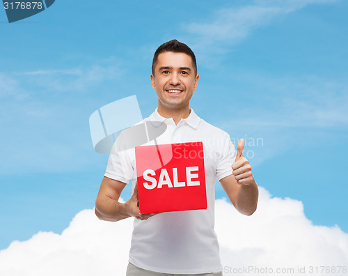 Image of smiling man with red sale sigh showing thumbs up