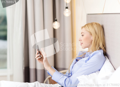 Image of happy businesswoman with smartphone in hotel room