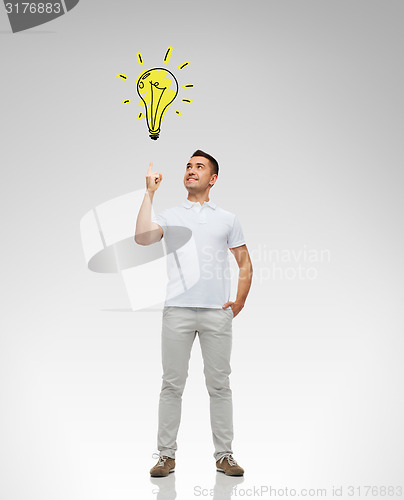 Image of smiling man pointing finger to lighting bulb