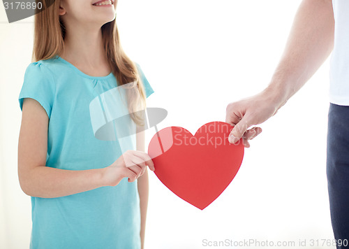 Image of close up of girl and male hand holding red heart