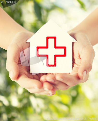 Image of hands holding paper house with red cross