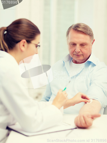 Image of female doctor doing injection to old man