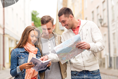 Image of group of smiling friends with city guide and map