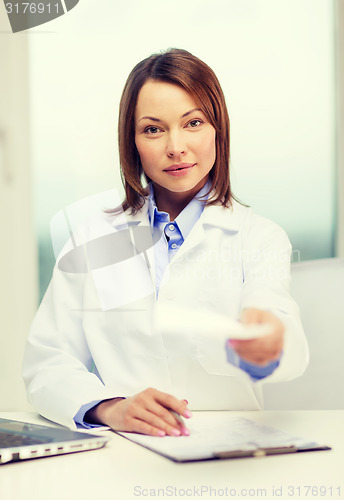 Image of busy doctor with laptop computer and clipboard