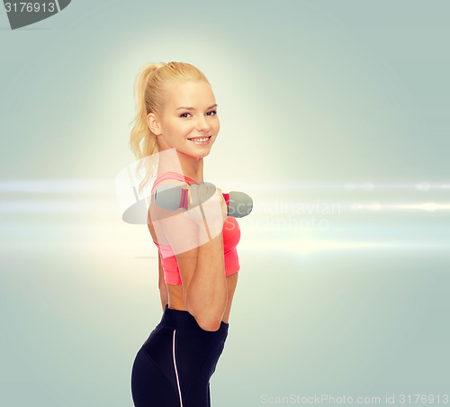 Image of smiling beautiful sporty woman with dumbbell