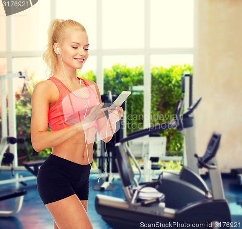 Image of smiling sporty woman with smartphone and earphones