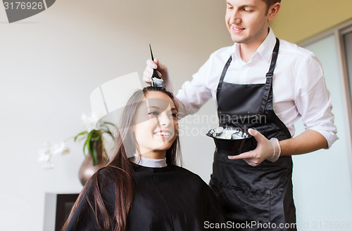 Image of happy young woman coloring hair at salon