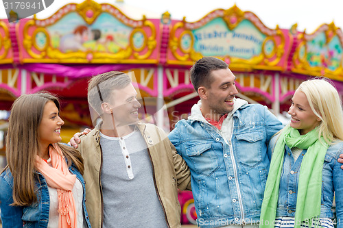 Image of group of smiling friends in amusement park