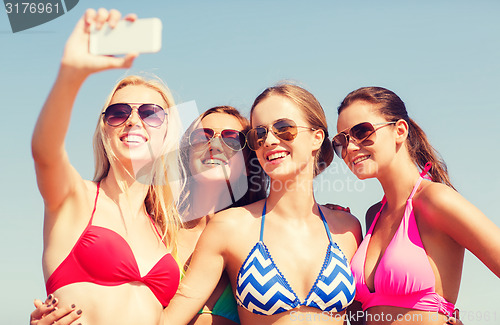 Image of group of smiling women making selfie on beach