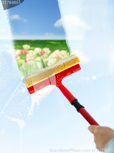 Image of close up of hand cleaning window with sponge