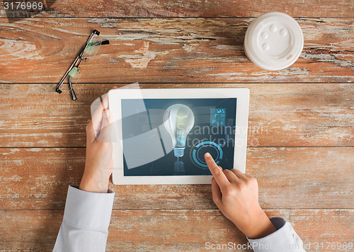 Image of close up of hands with tablet pc and lighting bulb