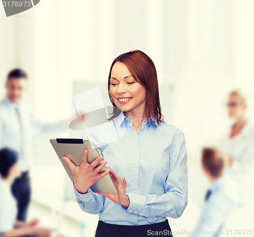 Image of smiling woman looking at tablet pc at office