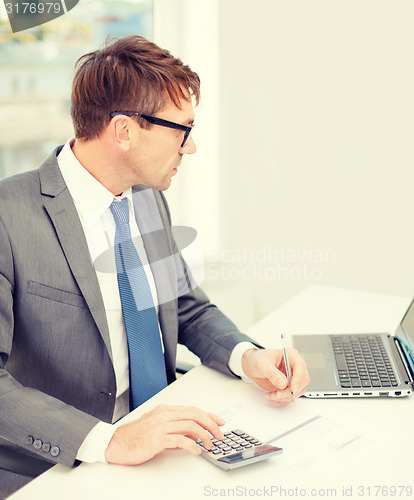 Image of businessman with computer, papers and calculator