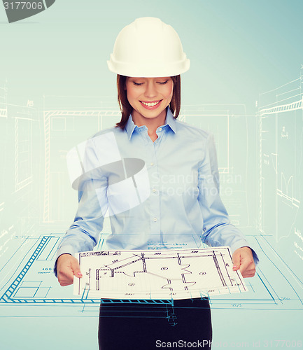 Image of businesswoman in helmet looking at blueprint