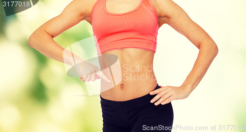 Image of close up of woman pointing finger at her six pack