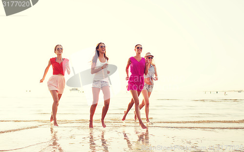 Image of group of smiling women running on beach