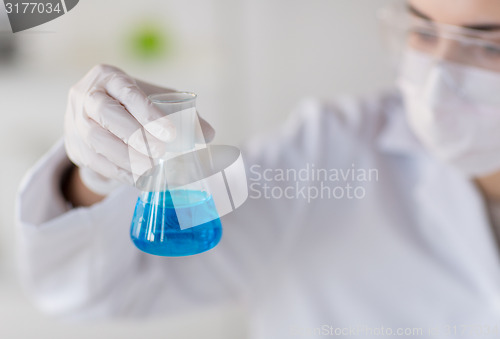 Image of close up of woman with flask making test in lab