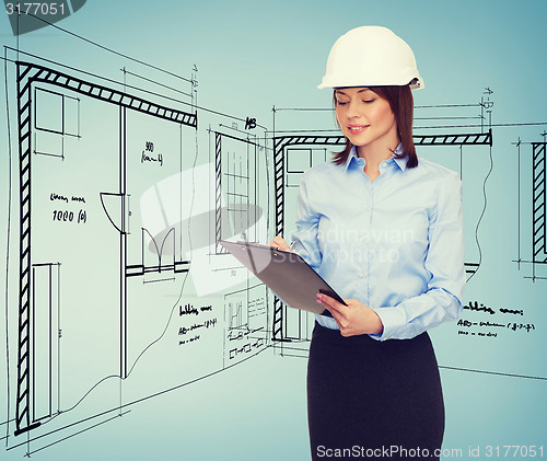 Image of smiling businesswoman in helmet with clipboard