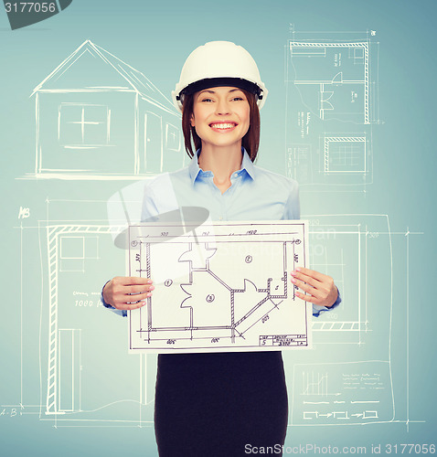 Image of smiling businesswoman in helmet showing blueprint