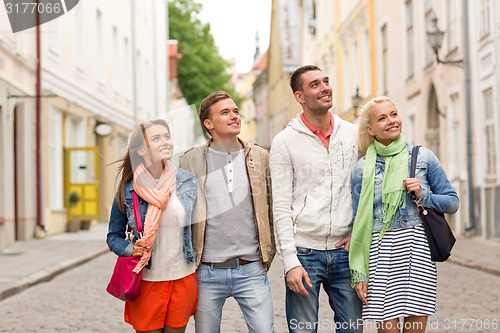 Image of group of smiling friends walking in the city