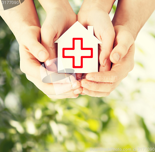 Image of hands holding paper house with red cross