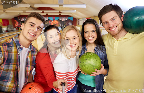 Image of happy friends taking selfie in bowling club