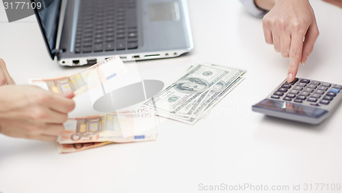 Image of close up of hands counting money with calculator