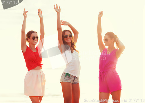 Image of group of smiling women dancing on beach