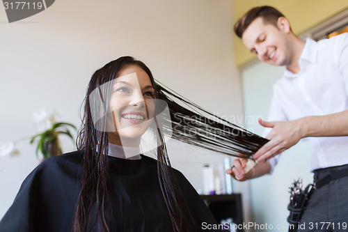 Image of happy woman with stylist cutting hair at salon