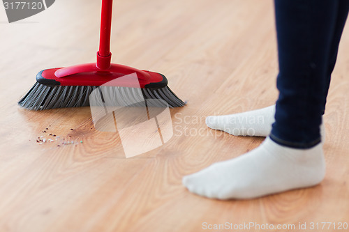 Image of close up of woman legs with broom sweeping floor