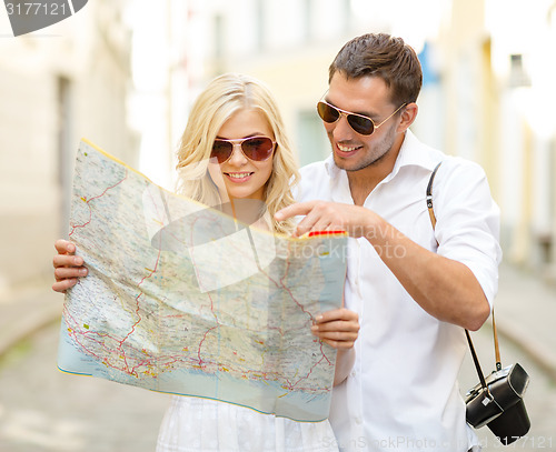 Image of smiling couple in sunglasses with map in the city