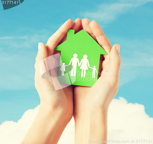 Image of hands holding green house with family