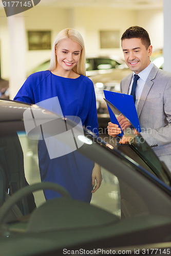 Image of happy woman with car dealer in auto show or salon