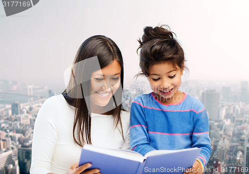 Image of happy mother and little daughter reading book