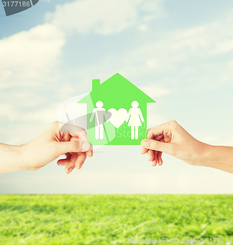 Image of hands holding green house with family