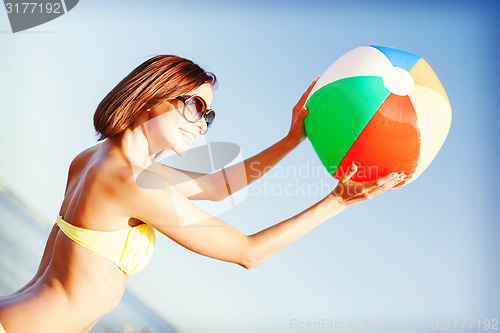 Image of girl in bikini playing ball on the beach